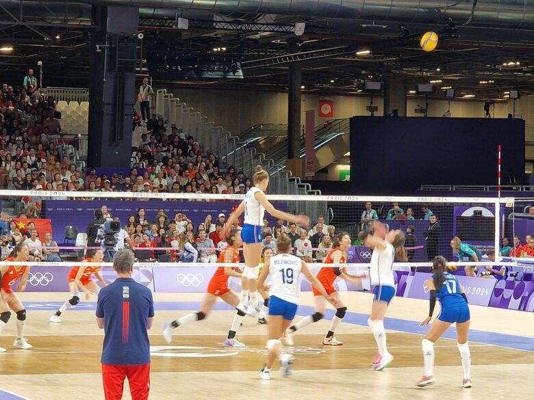 A player from the Sebian Women's volleyball team prepares to hit the ball over the net.