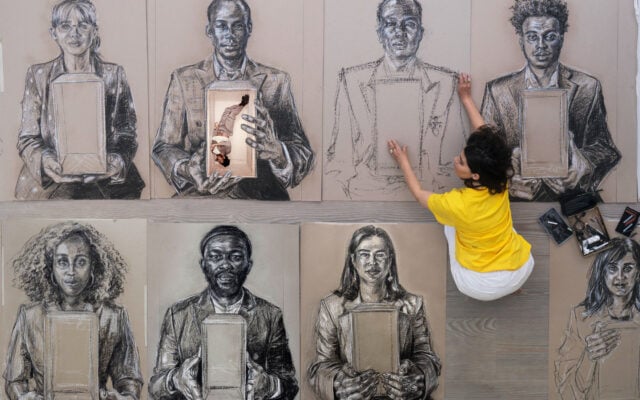 Es Devlin sitting amongst the portraits of 50 Londoners with refugee experience. These portraits will make up Congregation.